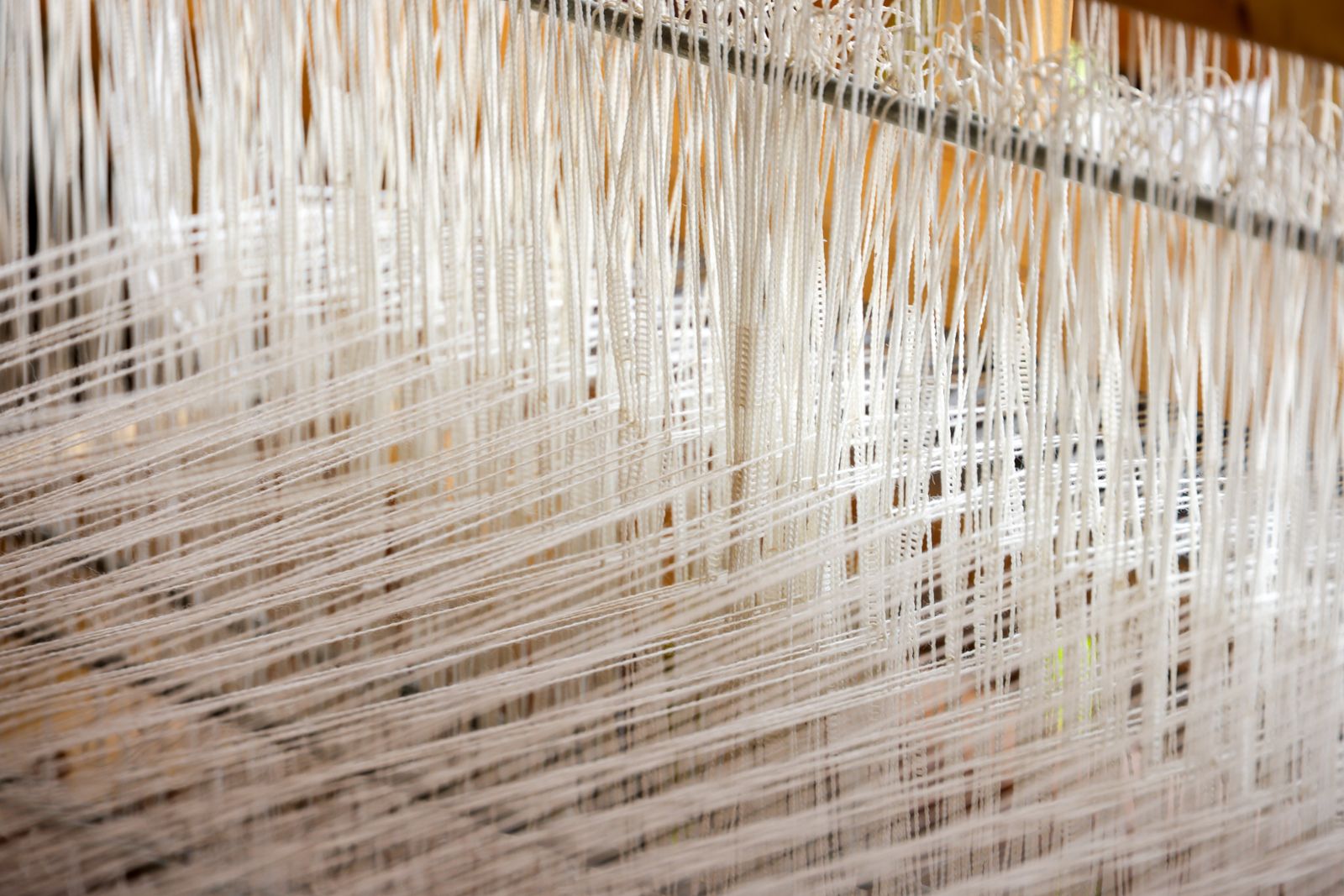 A length of Corriedale wool roving being drafted out between two hands in preparation for spinning on a drop spindle