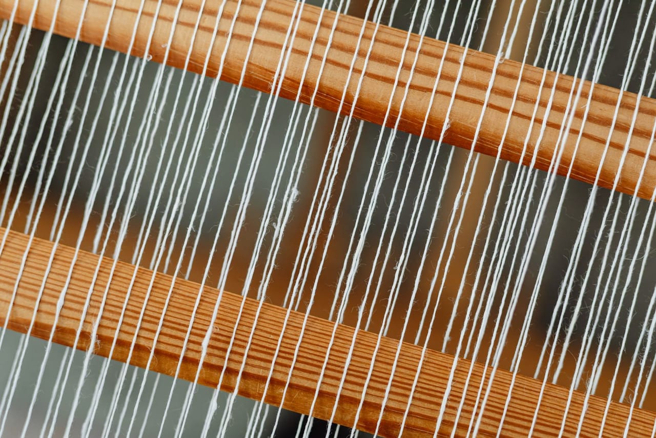 Two strands of handspun singles being plied together on a drop spindle, twisting counter-clockwise to form balanced 2-ply yarn