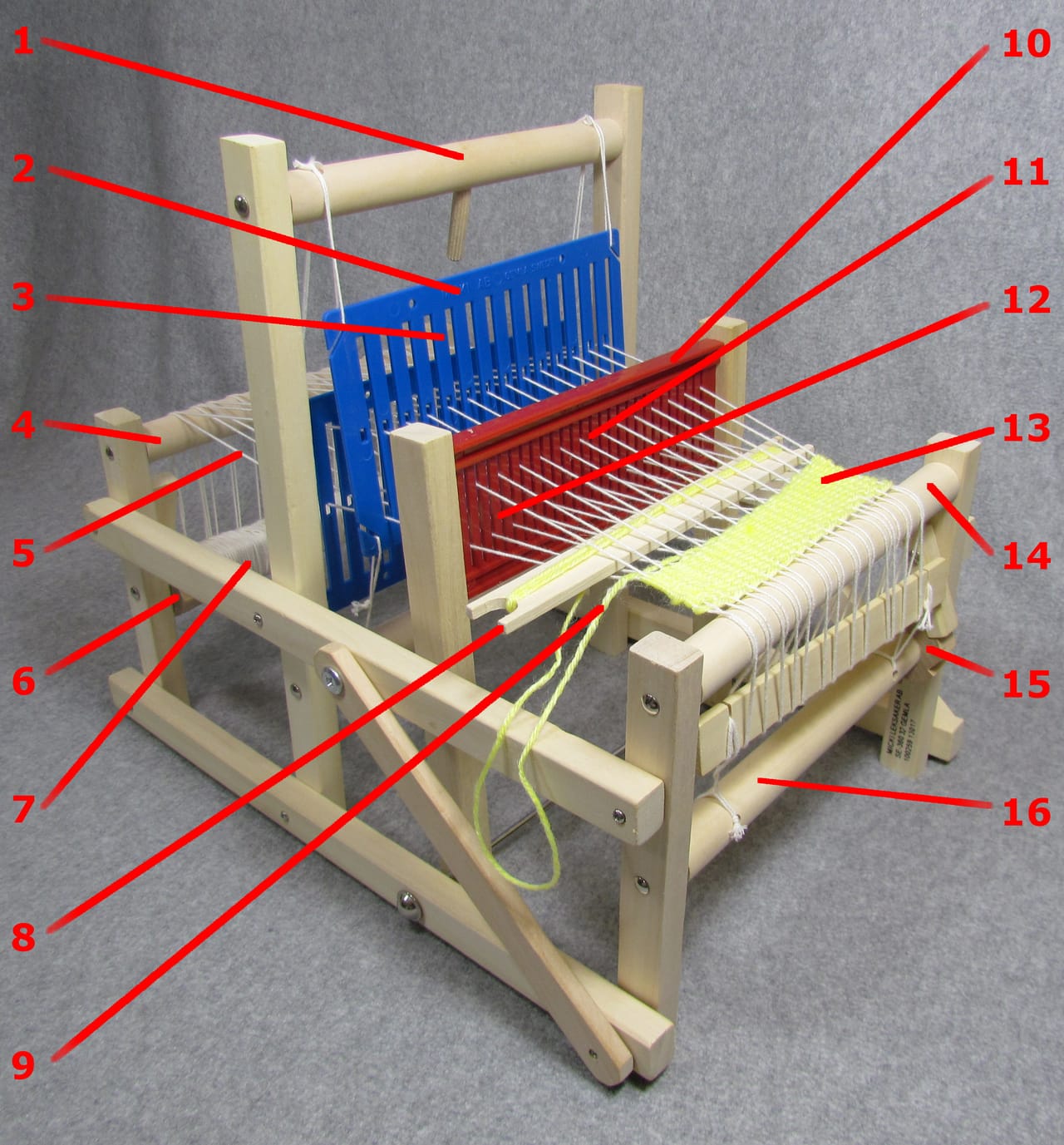 Labeled diagram of a rigid heddle loom showing the heddle with its holes and slots, the warp beam at back, cloth beam at front, and the shuttle path through the open shed