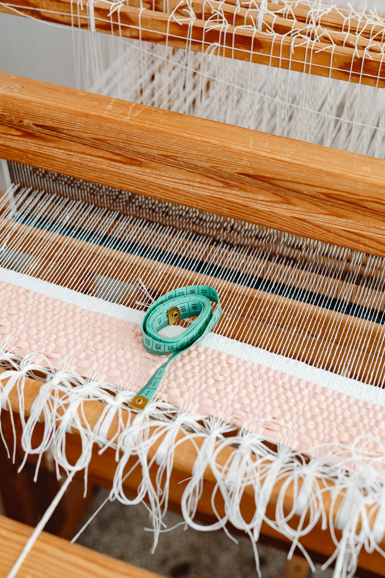 Several skeins of smooth DK and worsted weight yarn in natural and dyed colors laid on a wooden table, suitable for a first weaving project
