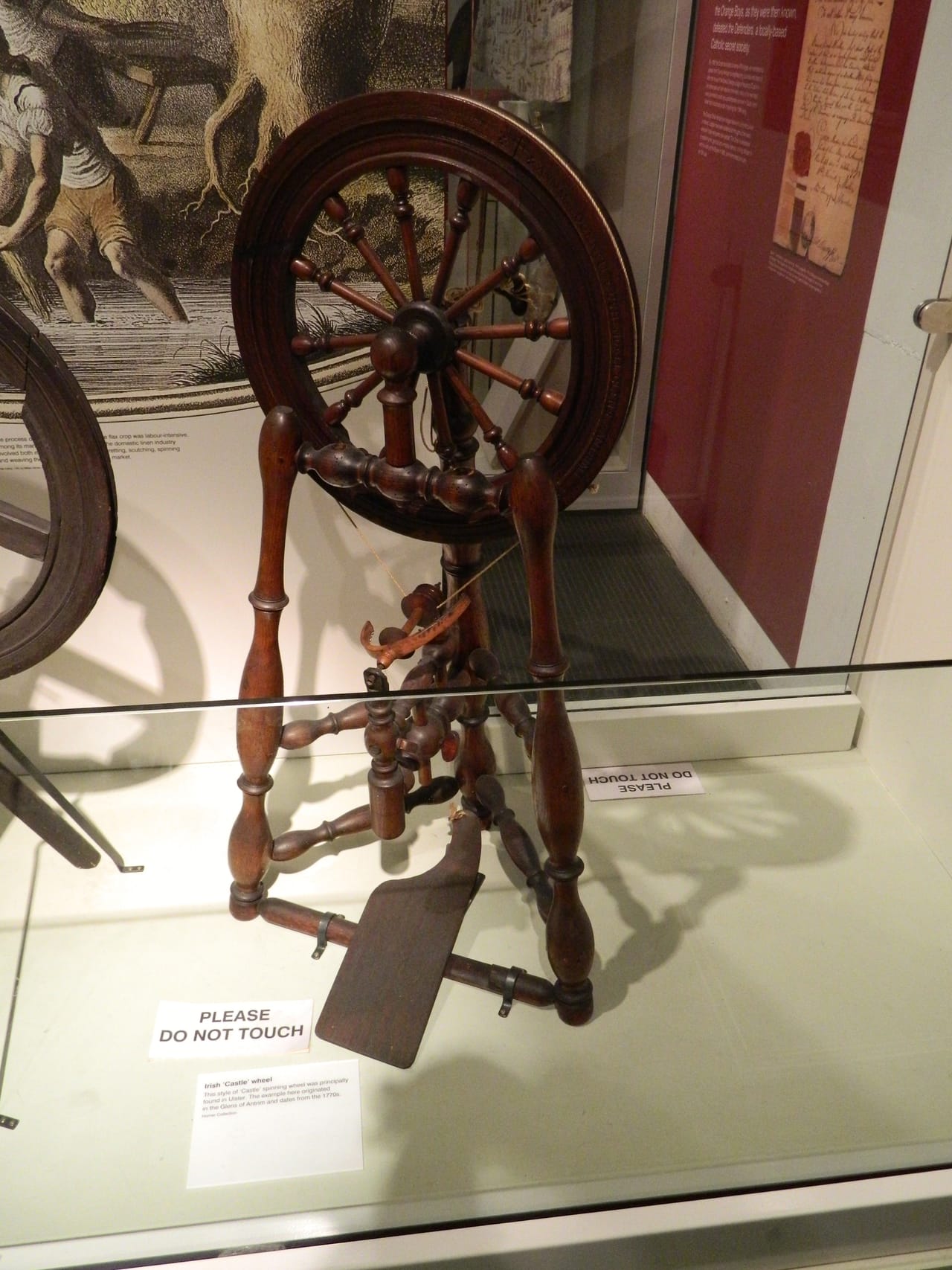 18th-century Irish castle-style spinning wheel at the Ulster Museum, Belfast, showing the vertical castle layout with flyer above the drive wheel