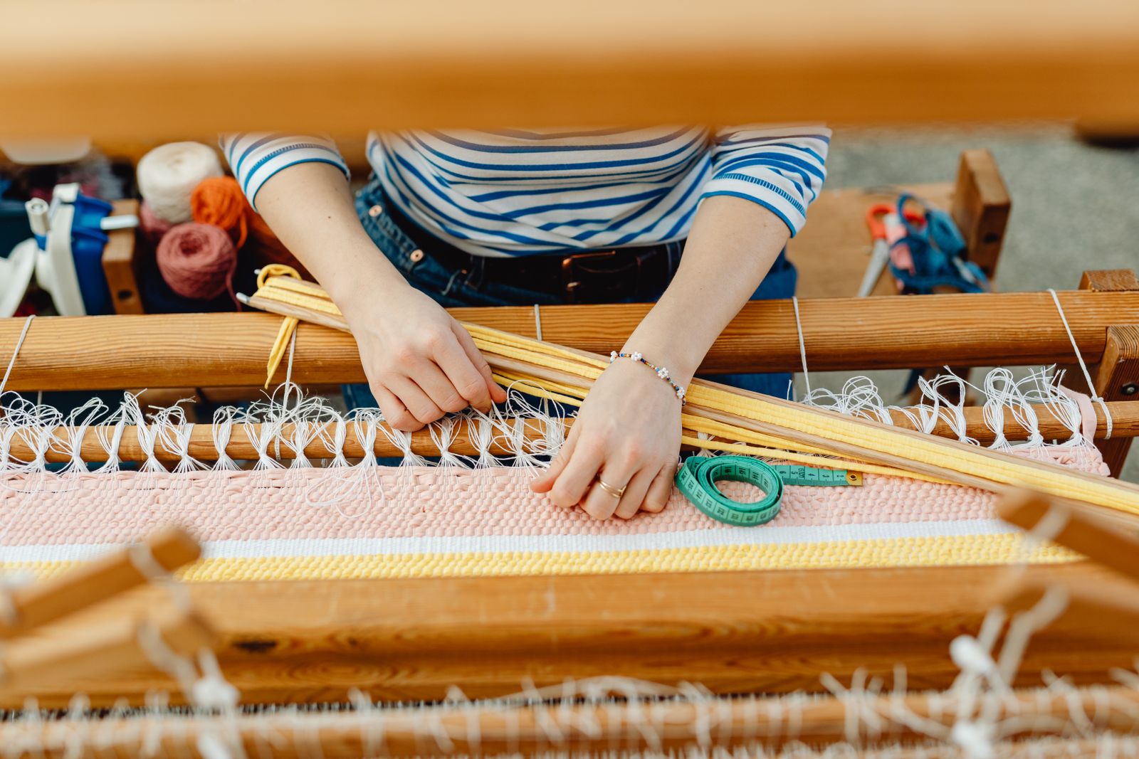 Table runner weaving in progress on a rigid heddle loom, the weft building row by row across the width of the frame